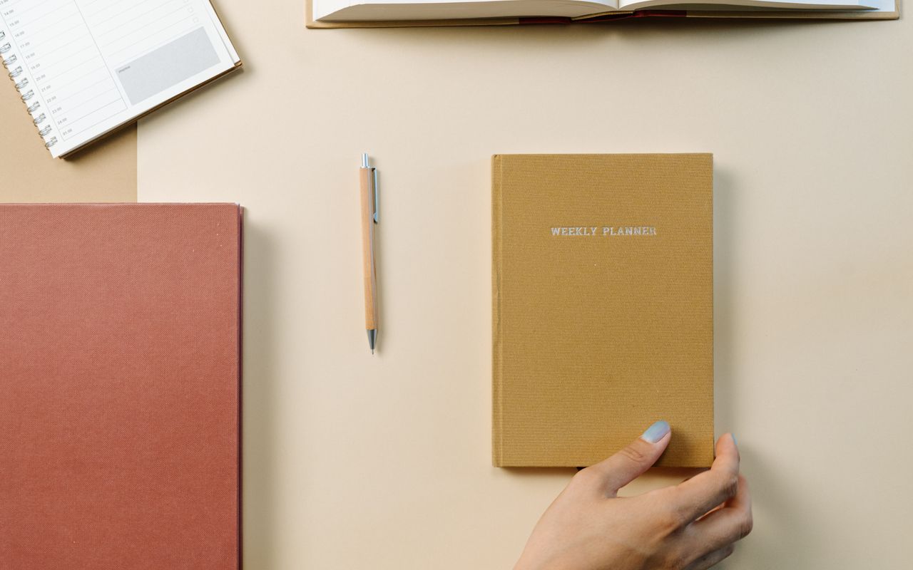 Mesa com agenda semanal, caderno e caneta